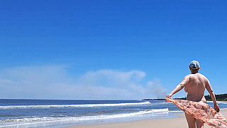 Amateur filming. A nudist plays with waves on the ocean shore.